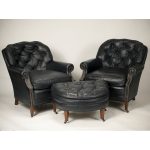 Two midnight blue button tufted leather club chairs with ottoman