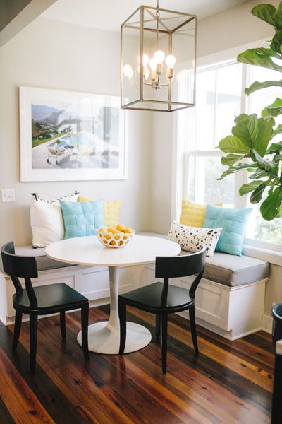 Round table and corner banquette dining area | bright pillows