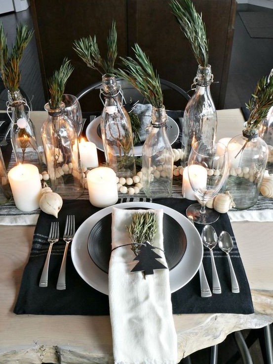 a Nordic Christmas tablescape with candles, beads, a black placemat, greenery in bottles for a natural feel