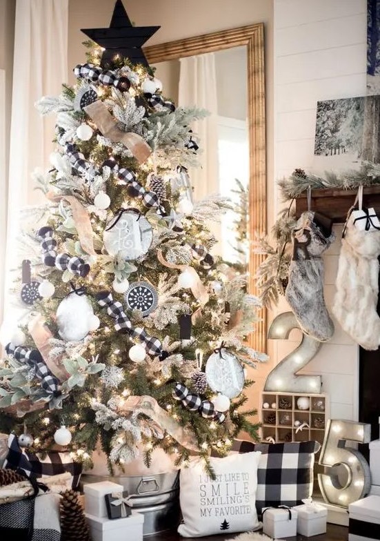 a bold black and white rustic Christmas tree decorated with buffalo check and burlap ribbons, black and white ornaments, lights, an oversized black plywood star topper is amazing