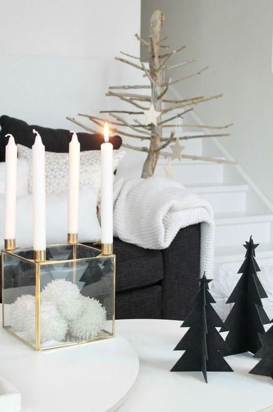 a clear box with white pompoms and candles on each corner, black cardboard Christmas trees and a tree with wooden stars