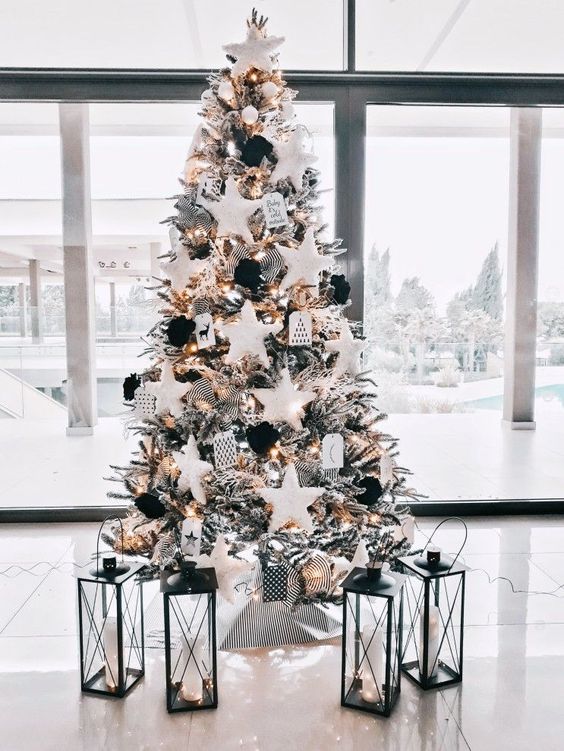 a flocked Christmas tree with oversized stars and black ornaments, ribbon, lights and many other details that add interest to it