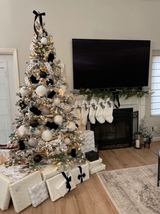 a flocked Christmas tree with white and black ornaments, ribbons, lights and a ribbon bow on top