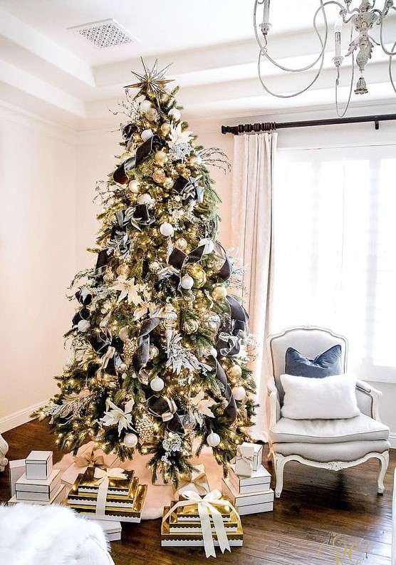 a glam Christmas tree decorated with white and gold ornaments, with black ribbon with white rims and white fabric blooms