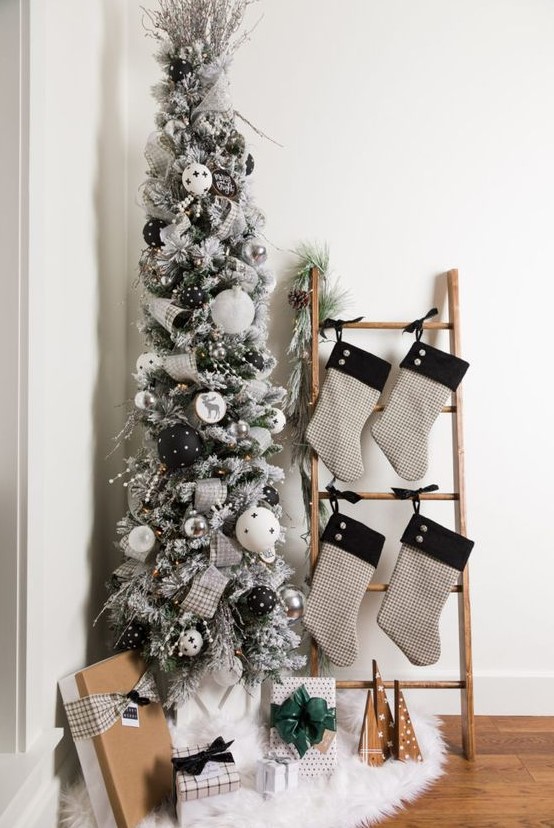 a modern flocked Christmas tree with white, black and silver ornaments, silver plaid ribbons and some berries is lovely