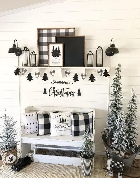 a pretty black and white Christmas entryway with a white bench, a shelf with signs, lanterns, a Christmas tree banner and snowy Christmas trees