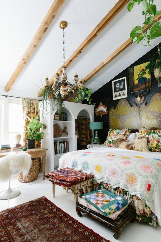 an eclectic bedroom with a bed and a statement headboard, bright textiles, a storage unit, a vintage desk, a fluffy chair and greenery