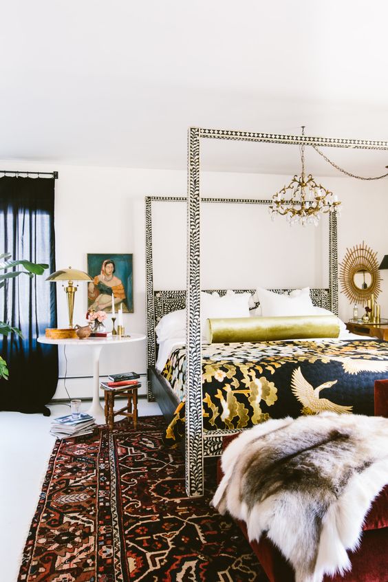an eclectic bedroom with an eye-catchy frame bed, a bold rug, mismatching nightstands and a vintage chandelier