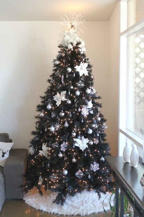an elegant Christmas tree with silver, black, sheer ornaments, fabric flowers and snowflakes, lights and a lit up topper