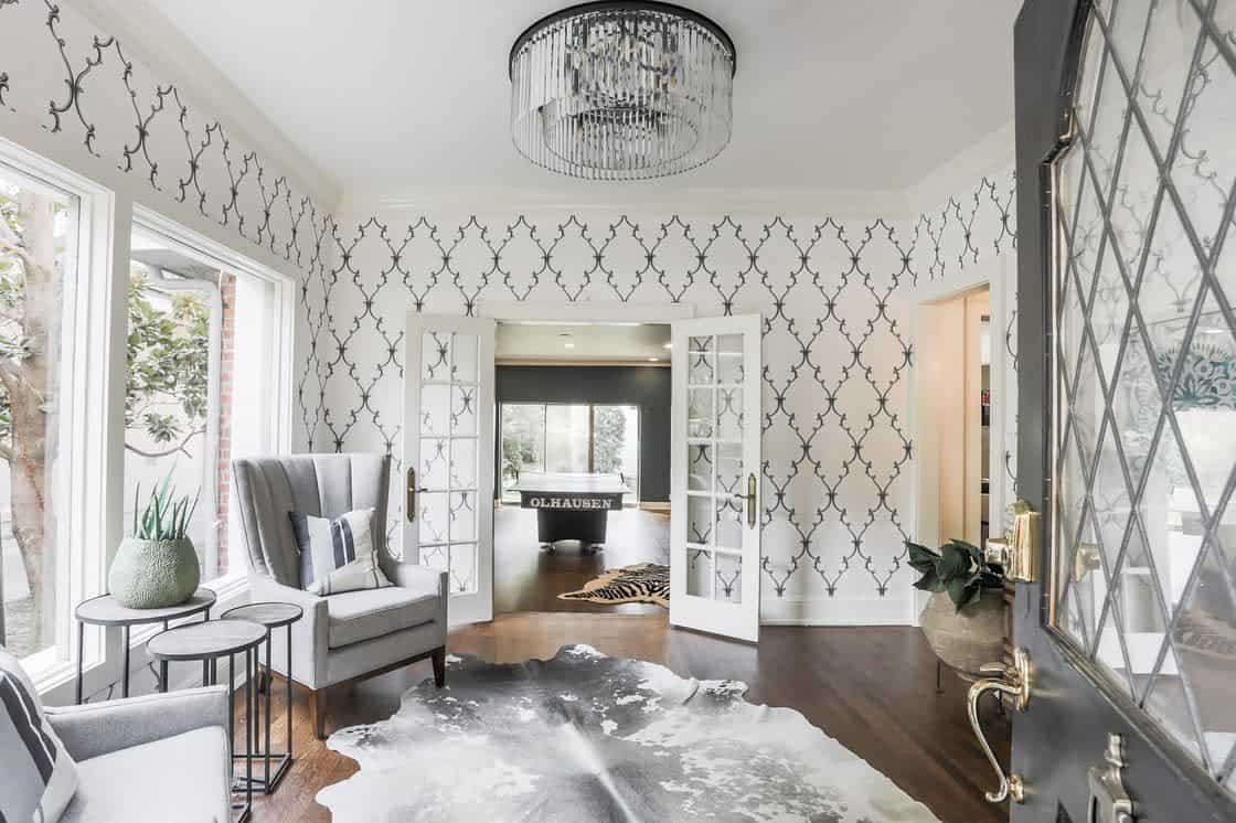 Living room with patterned wallpaper and gray chairs and cowhide floor carpet