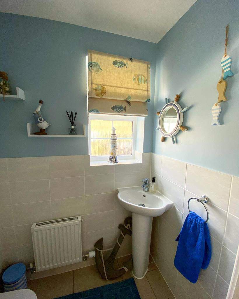 Bathroom with white tiles and blue walls and corner sink 