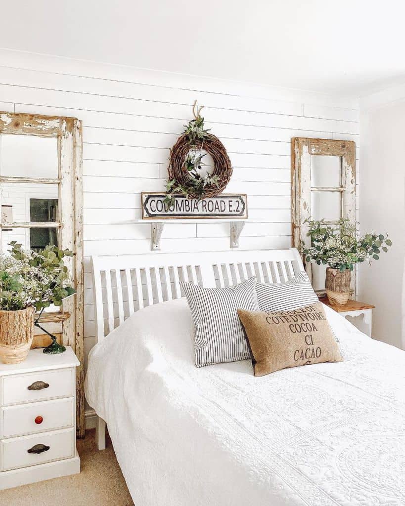 White country house bedroom with shiplap wall and two wall mirrors 