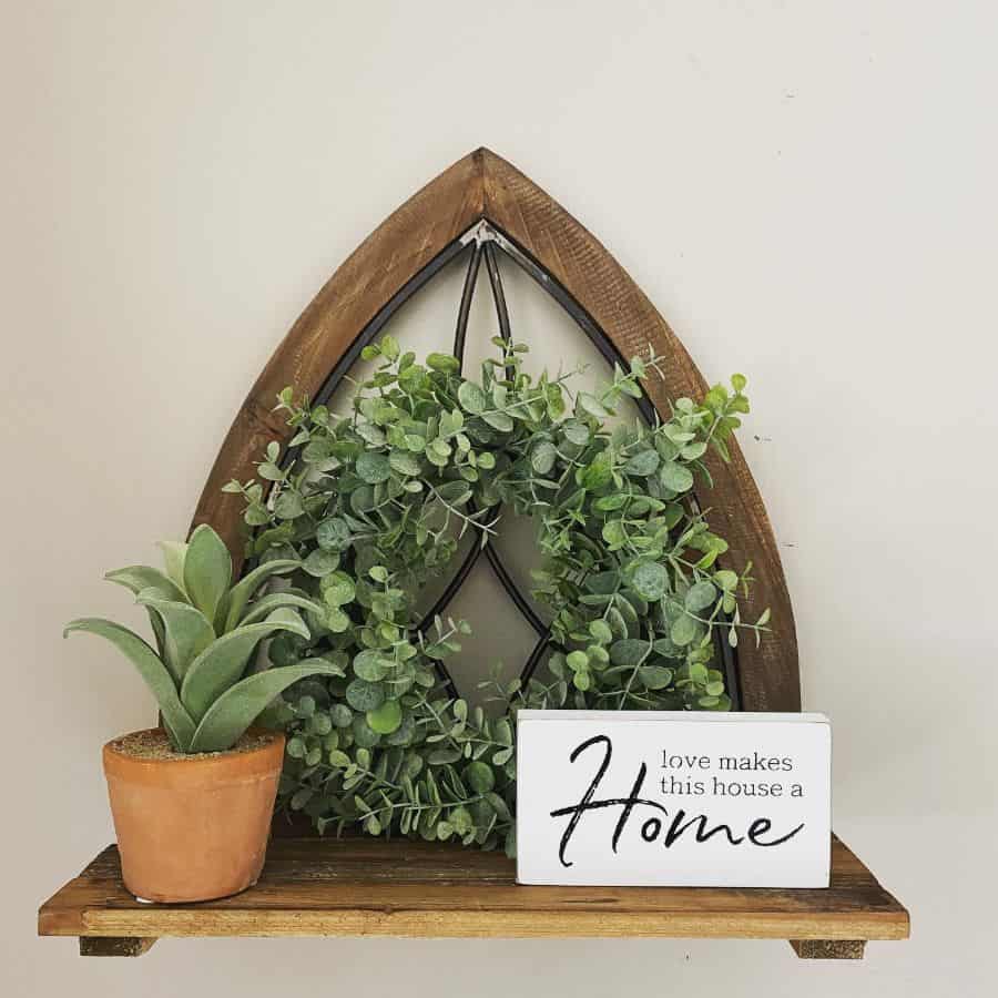 Wooden wall shelf with plants and sign 