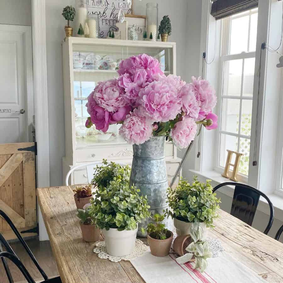 Modern farmhouse dining room with rustic wooden table and flowers 