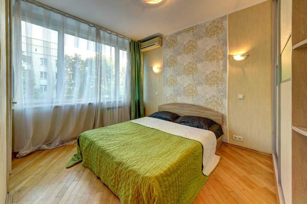 Floral print bedroom wallpaper, wooden floor, green bed