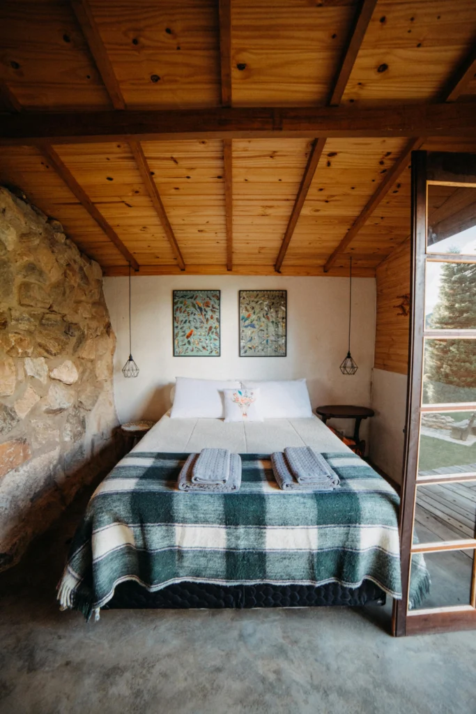 Rustic Cabin Bedroom with Stone Wall and Wood Ceiling