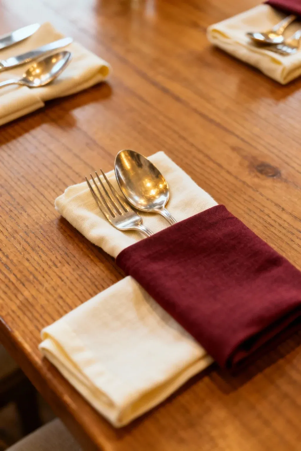 Silverware wrapped in cloth napkins, arranged elegantly on a wooden table.