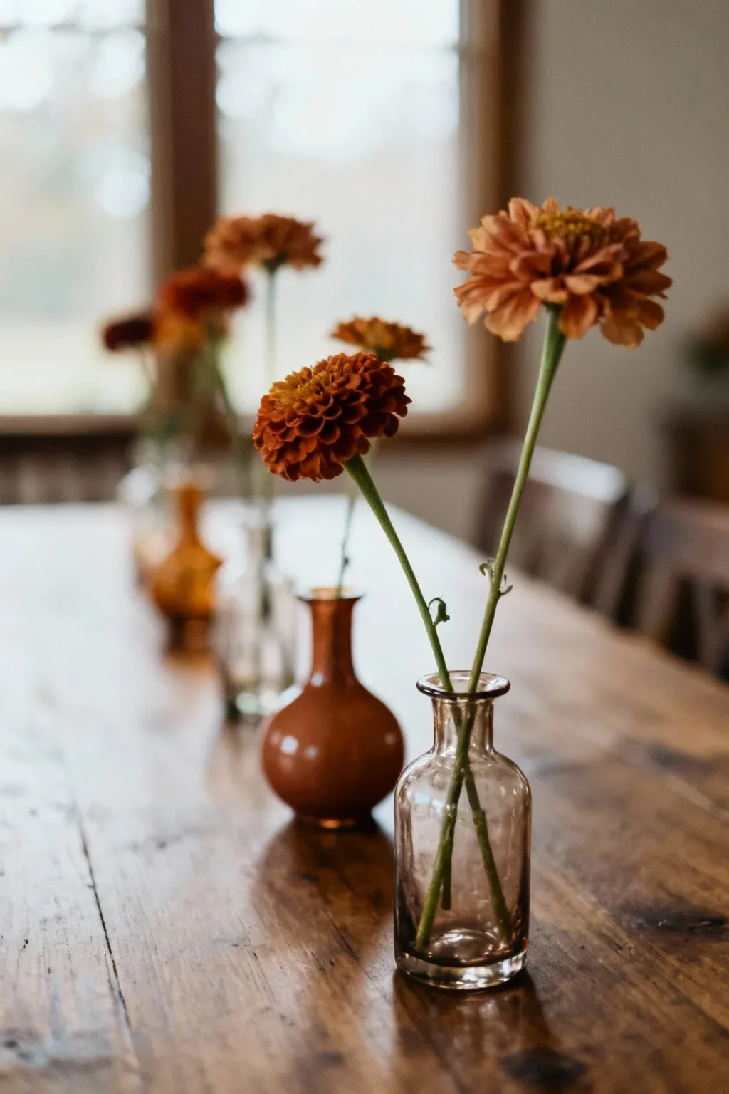 Simple glass vases with single stems of flowers arranged on a table.
