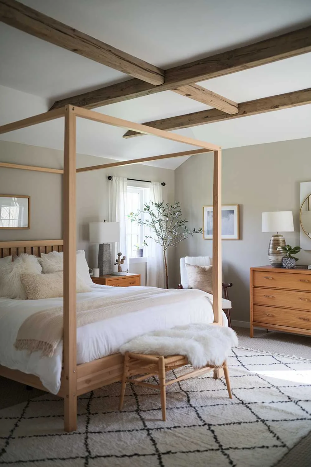 Scandinavian farmhouse bedroom featuring wooden beams, white bedding, wooden dresser, and indoor plant.