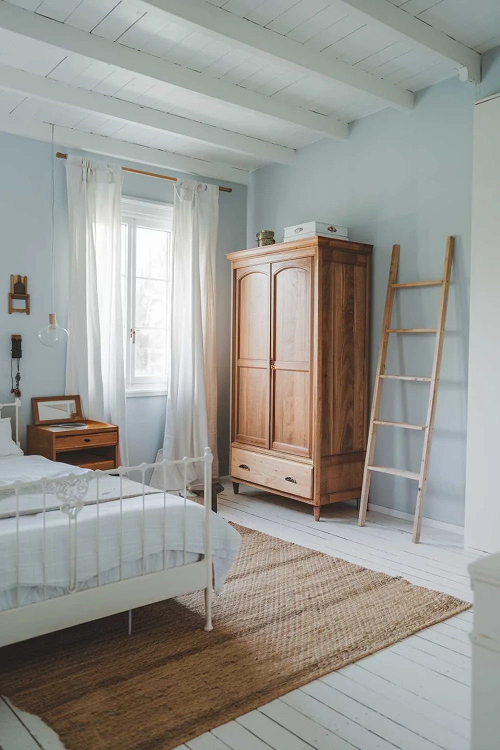 Scandinavian farmhouse bedroom with wooden furniture, white bed frame, wooden wardrobe, and wooden ladder.