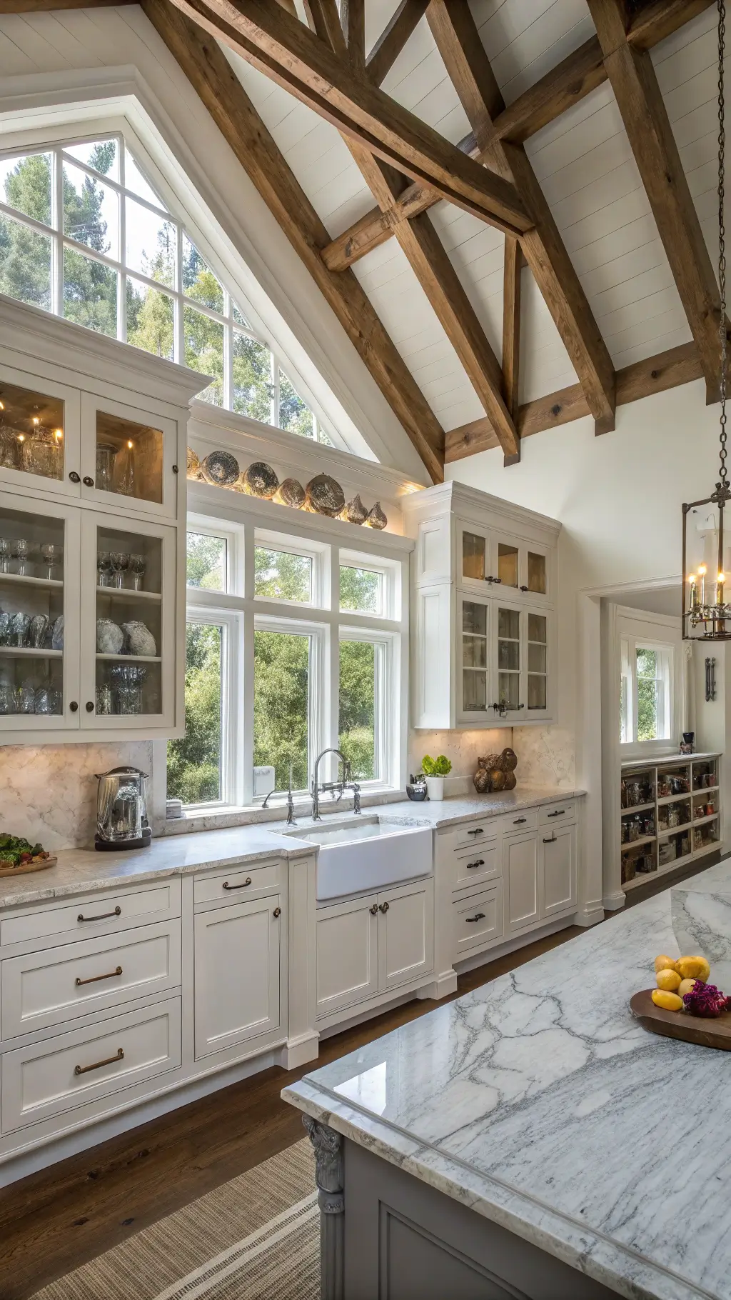 elegant farmhouse style kitchen with cathedral ceiling exposed beams marble counters vintage accessories on open shelving and natural light from clerestory windows.