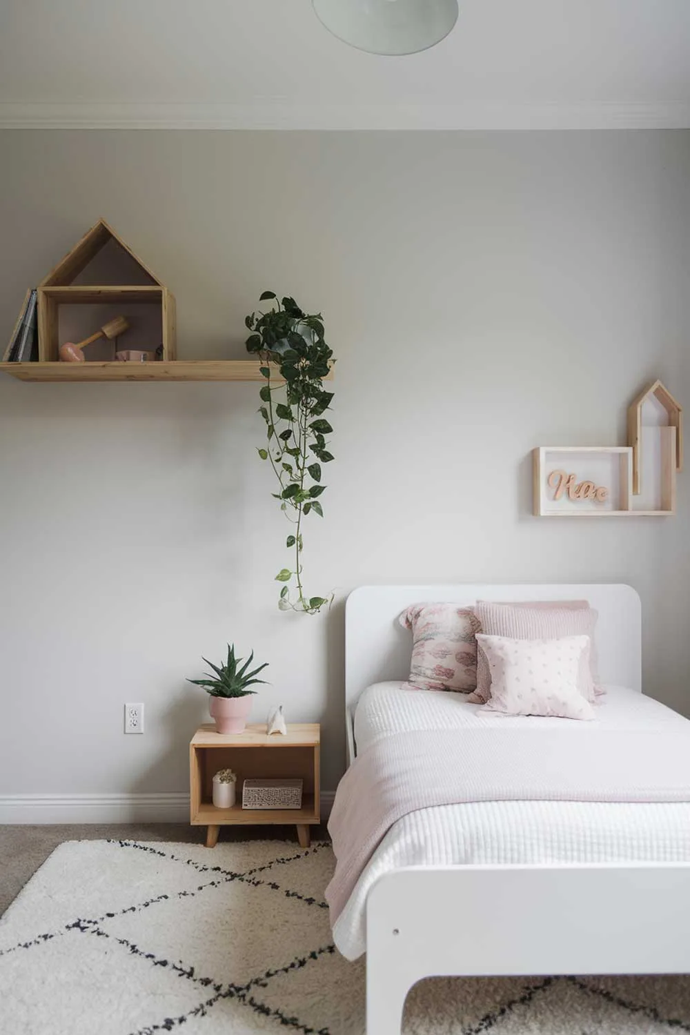 Minimalist girls bedroom with light gray walls and wooden shelf