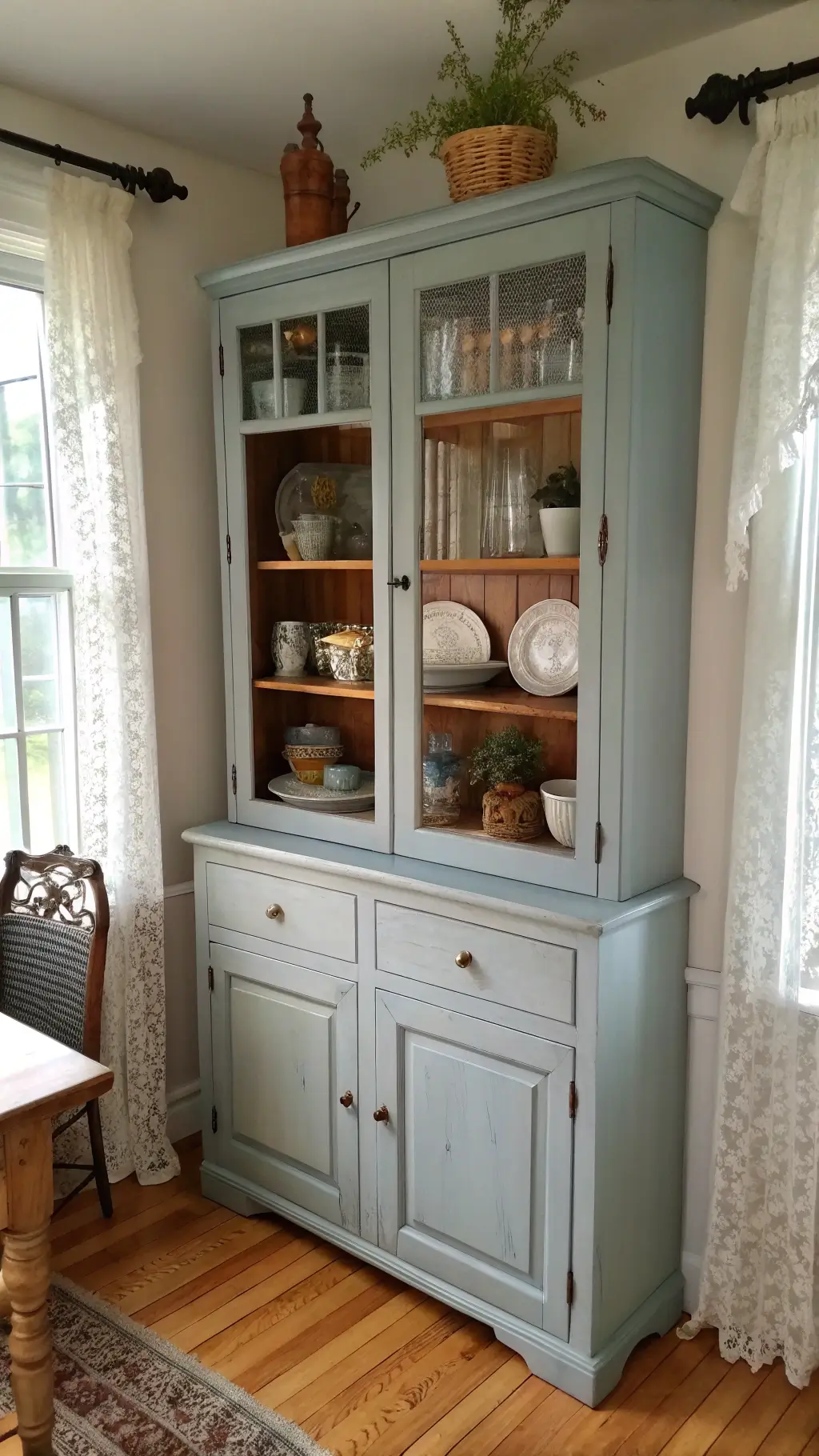 Blue-grey corner hutch styled with vintage accessories in a sunlit breakfast nook.