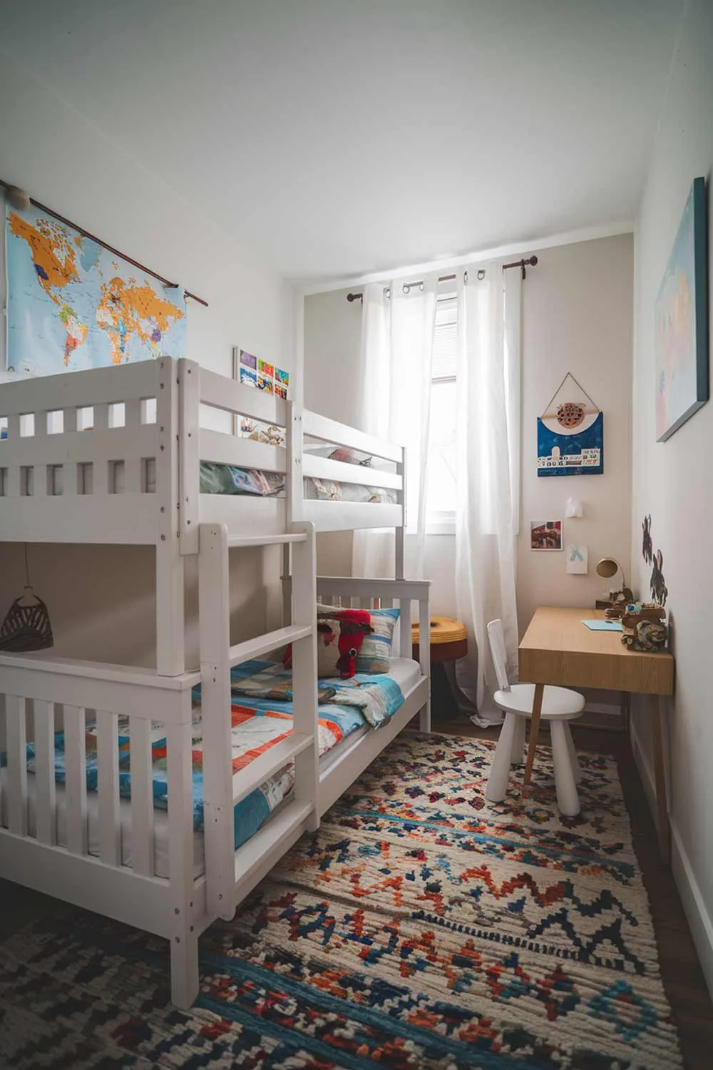 Minimalist kids bedroom with white wooden bunk bed and colorful rug