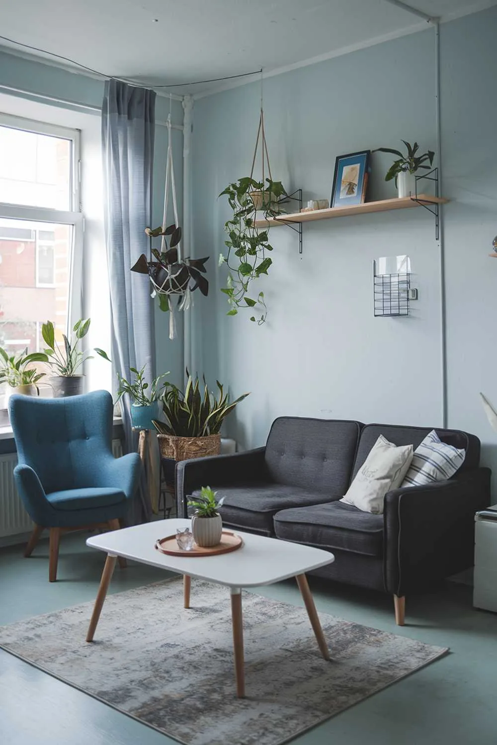 Scandinavian living room with dark grey sofa, blue chair, light blue walls, and hanging plants