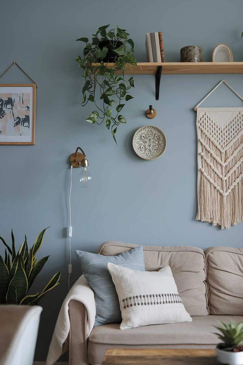 Small Scandinavian living room with beige sofa, wooden coffee table, wall shelf, potted plant, vintage lamp, and blue walls