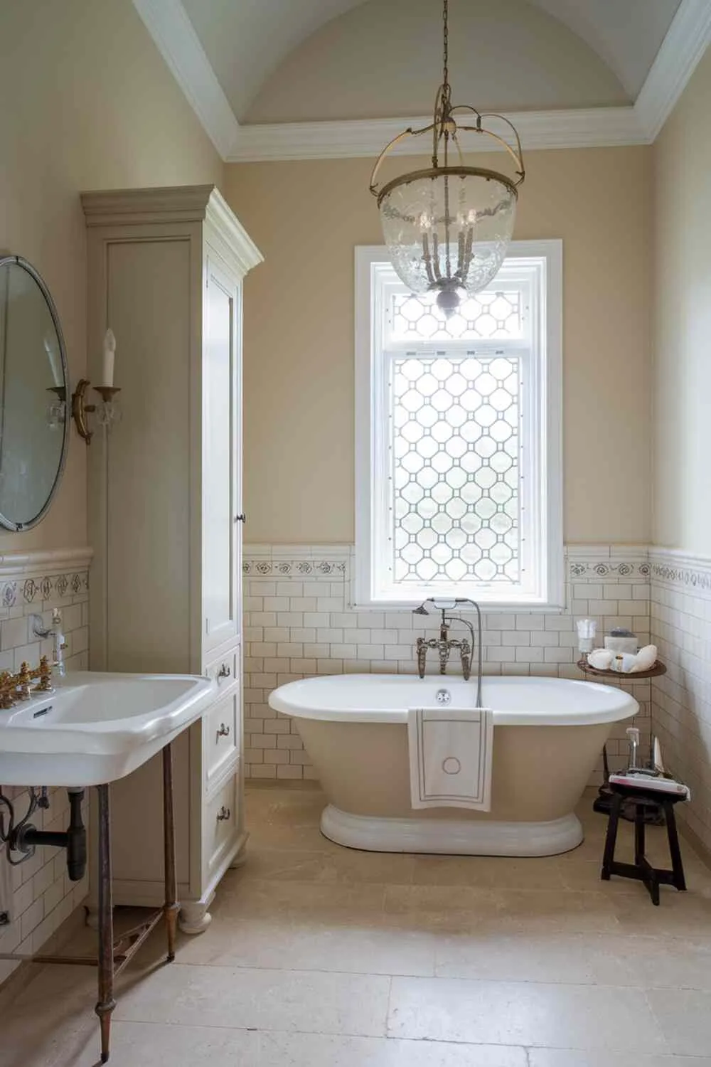 Classic bathroom with clawfoot tub, vintage sink, chandelier, and decorative window