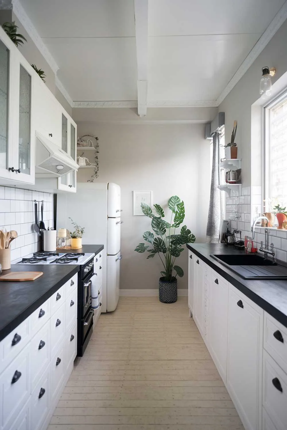 Scandinavian kitchen with white cabinets, black countertops, and light wood flooring