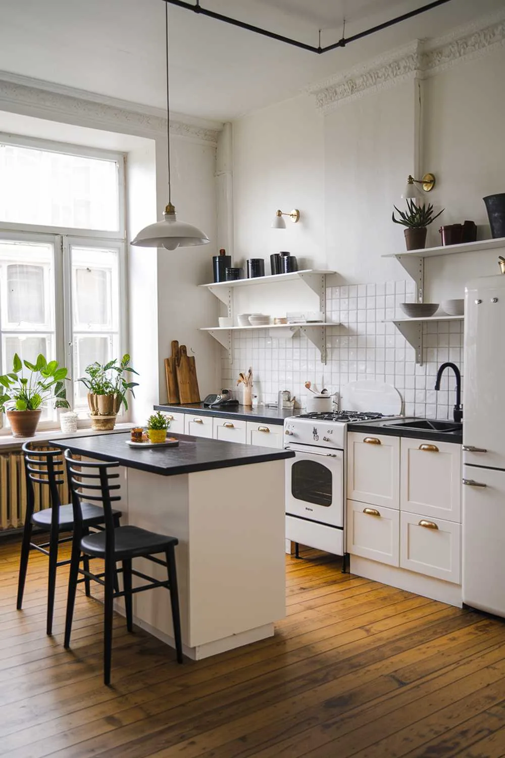 Scandinavian kitchen with white cabinets, brass handles, black countertop, and wooden floors