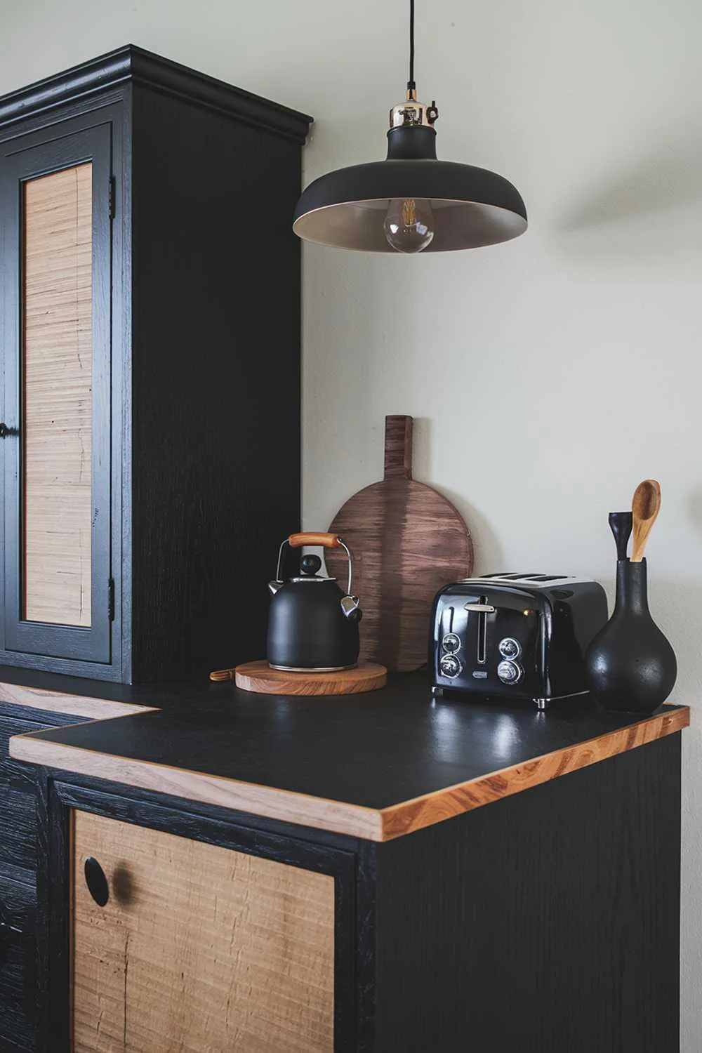 Minimalist kitchen with black countertops edged in wood, black cabinets, and wooden accents