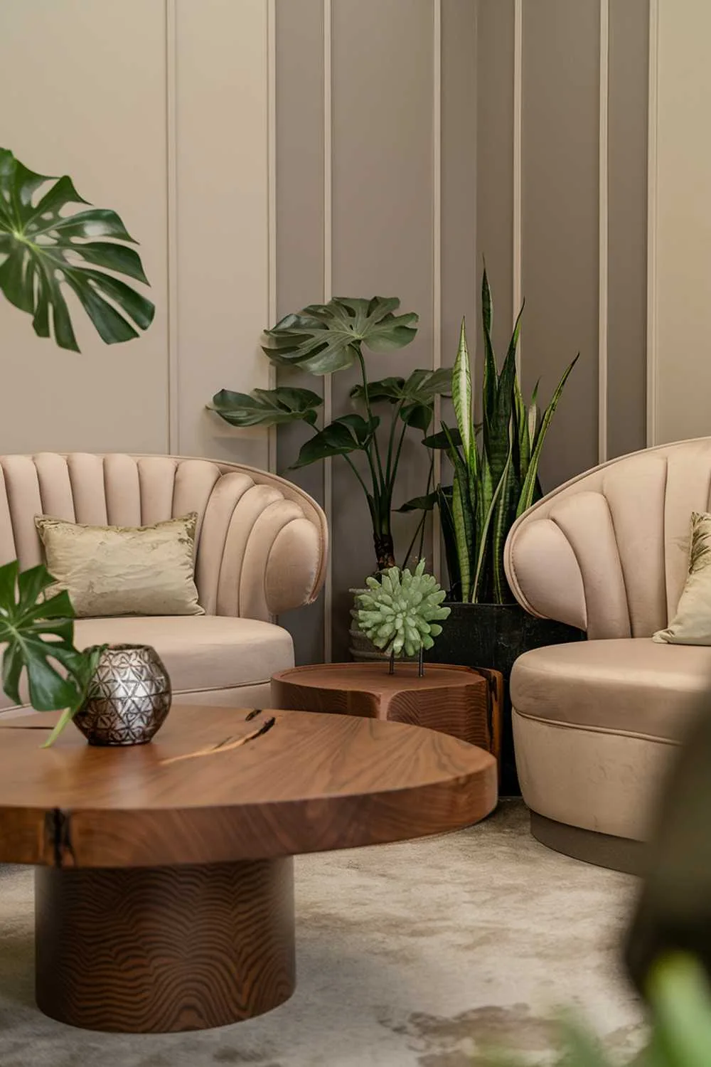 Beige sofa with curved backrest, wooden coffee table with circular base, monstera and snake plants, and patterned walls.