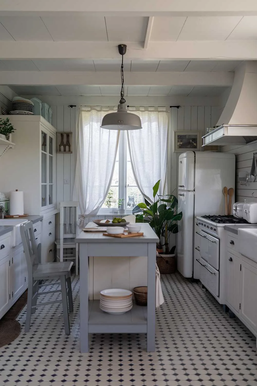 White kitchen with gray accents, checkered gray and white floor tiles, gray pendant light, and potted plant.