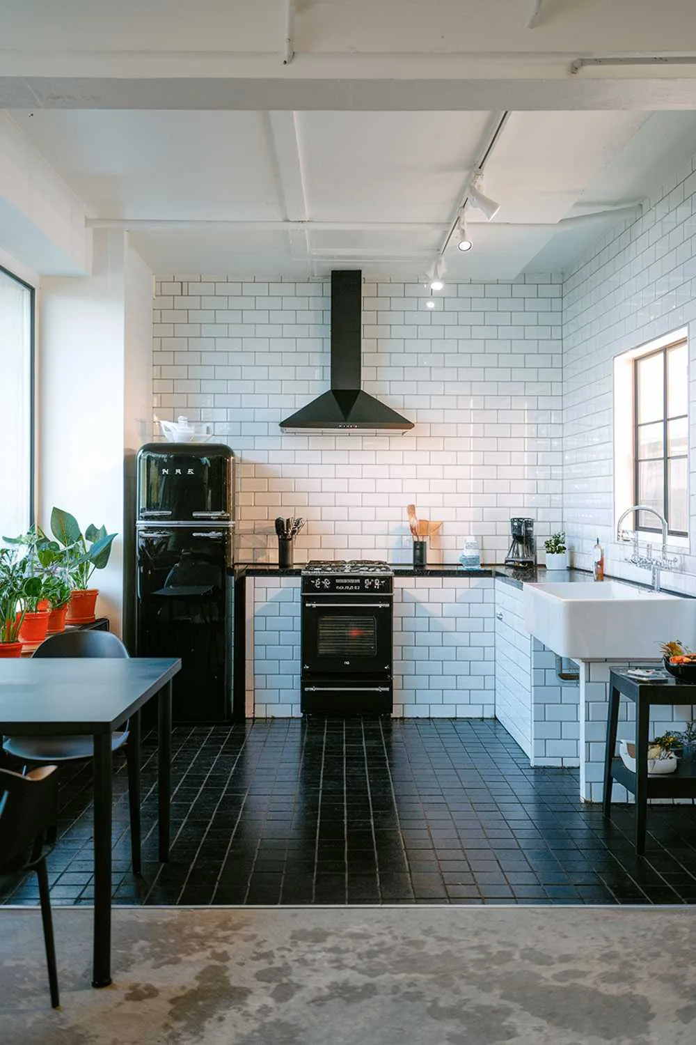 Minimalist kitchen with white subway tiles, black appliances, and urban decor