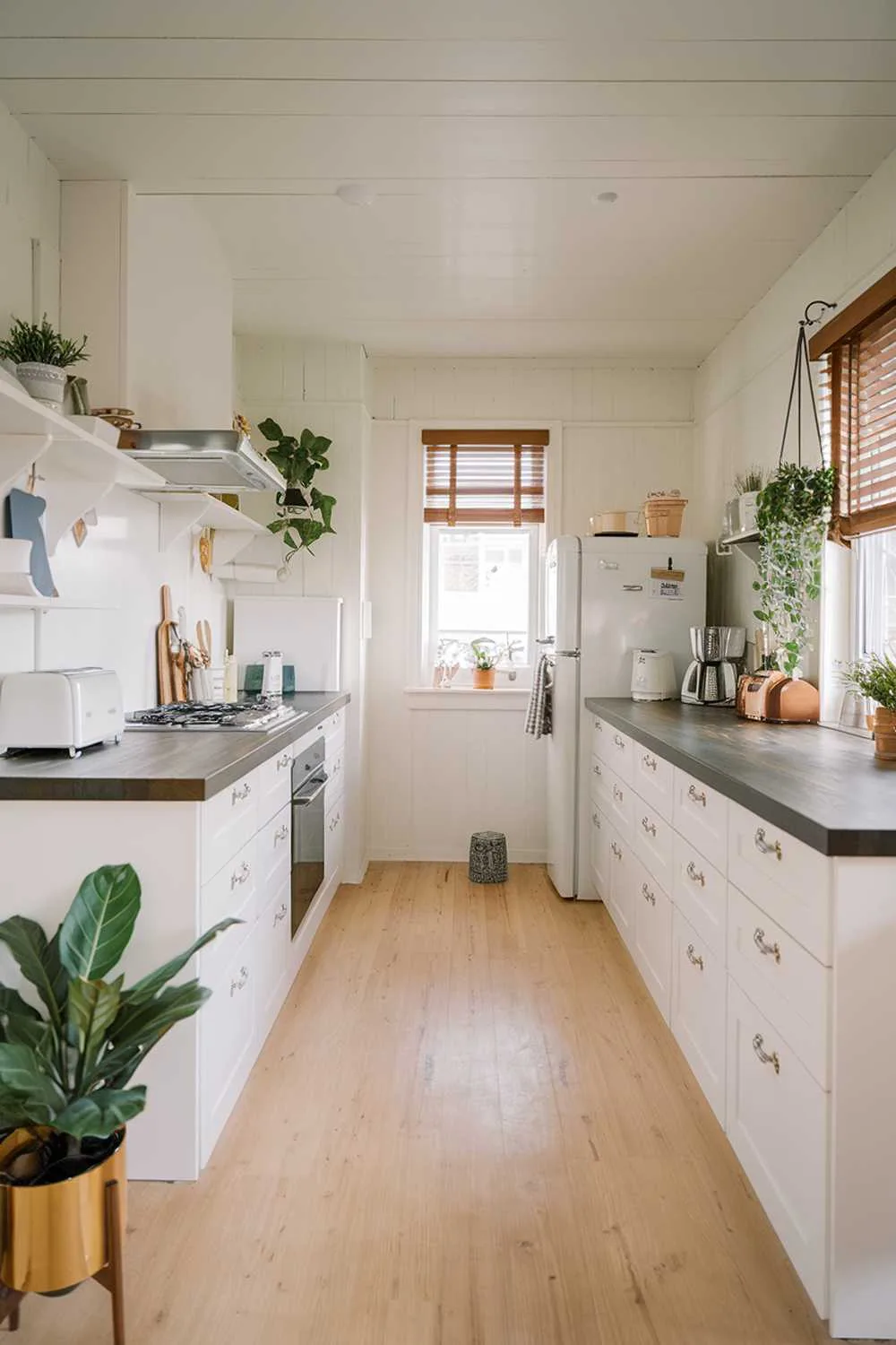 Minimalist kitchen with light wood floors, white cabinets, and dark countertops