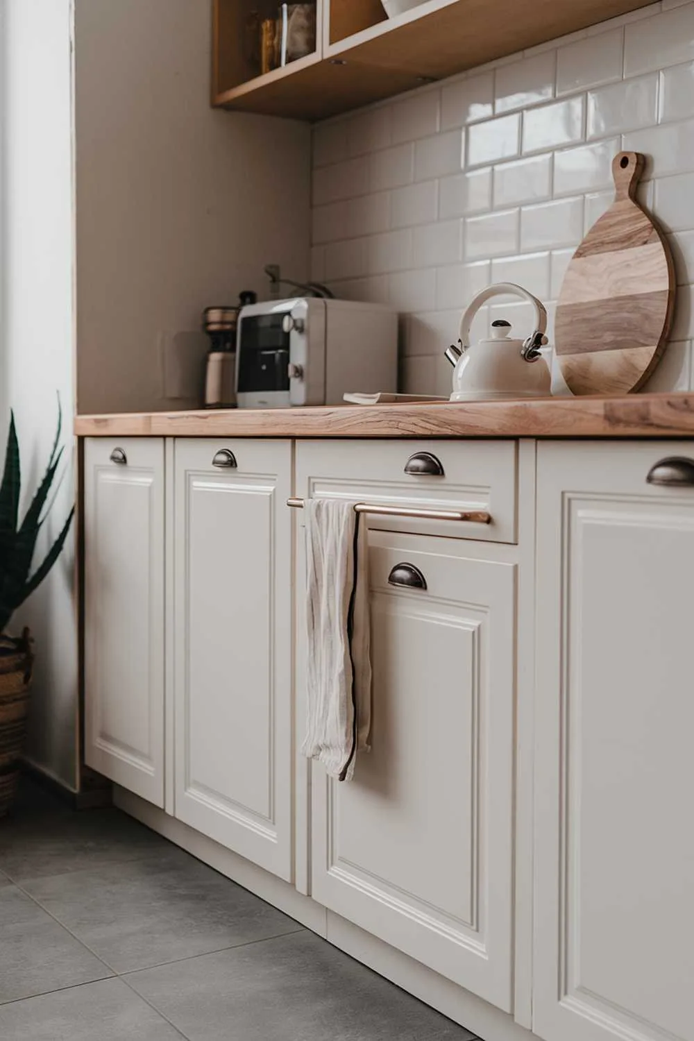 Minimalist kitchen with wooden countertop, white cabinets, and gray tiled floor