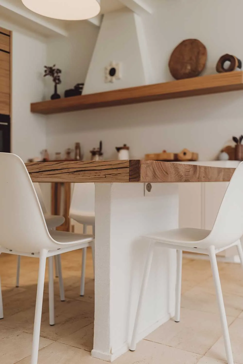 Minimalist kitchen with white island, wooden top, and surrounding chairs