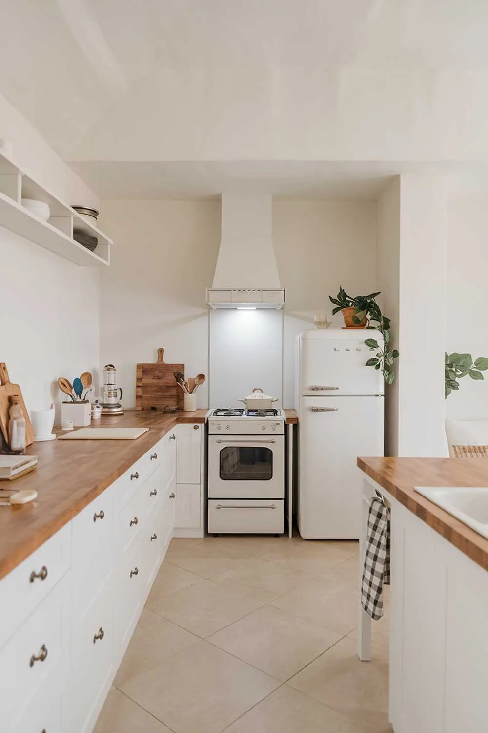 Minimalist kitchen with wooden countertop, white appliances, and beige tiles