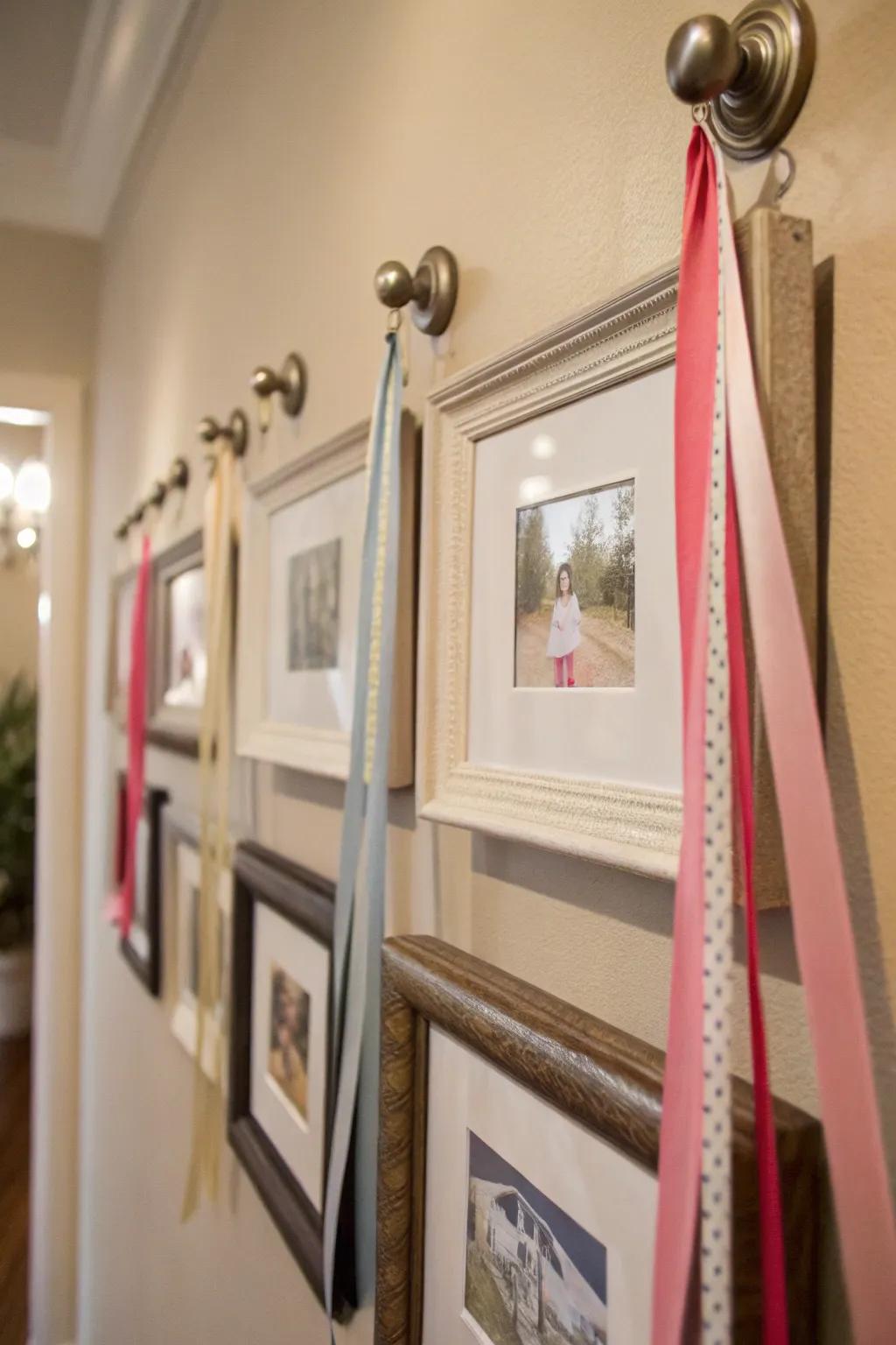 Creative wall arrangement featuring frames suspended from knobs with ribbons.