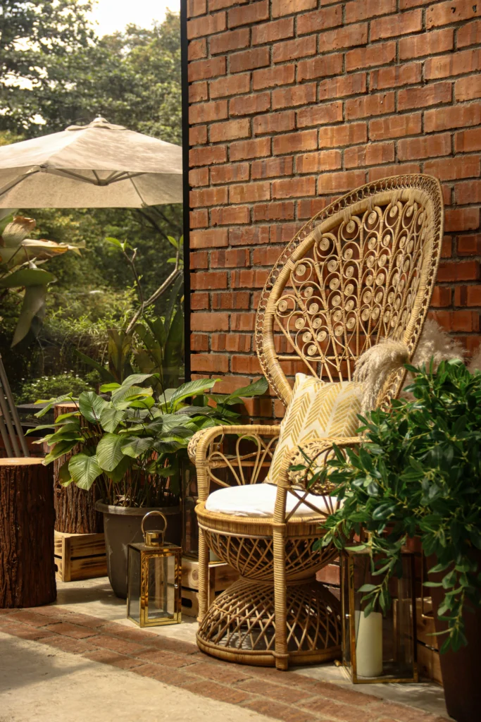 Elegant rattan peacock chair with lush plants and brass lanterns