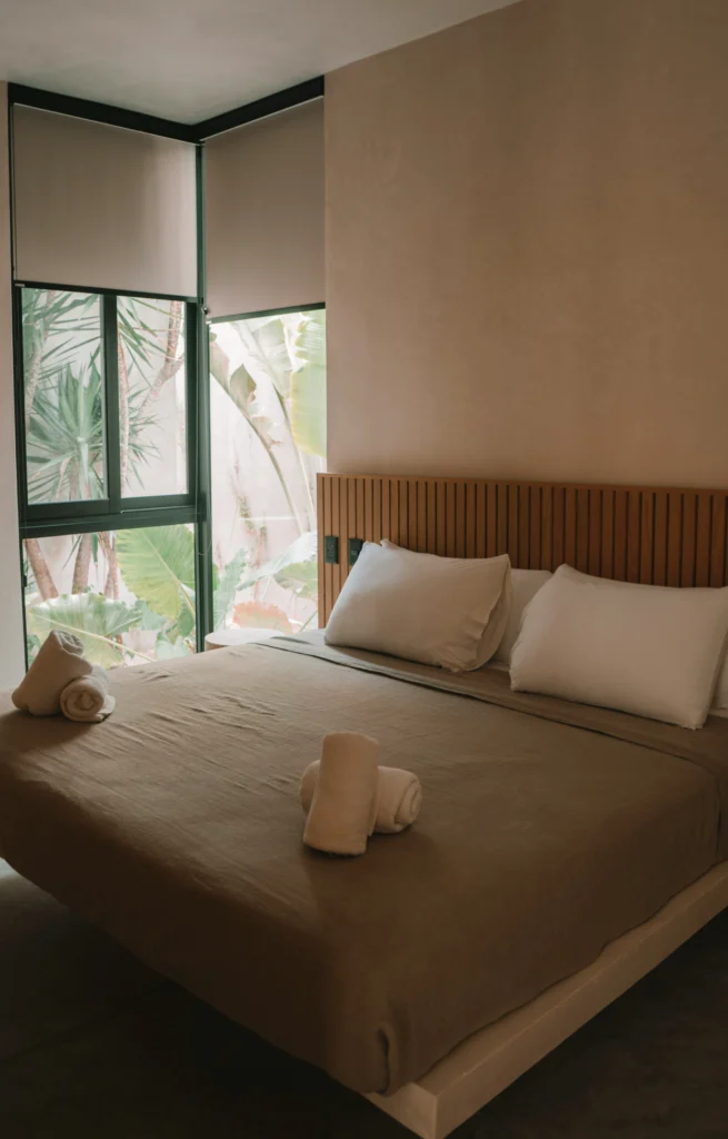 Tropical minimalist bedroom with large window and natural linens