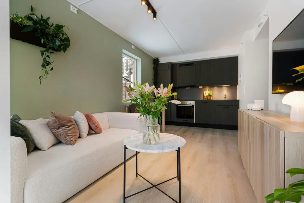 Airy living room with white sofa and sage green accent wall