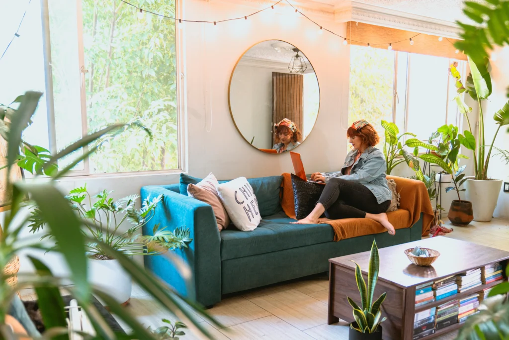 Teal sofa with plants and round mirror in boho living room