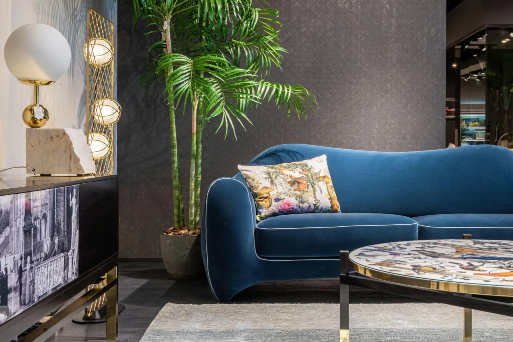 Blue velvet sofa with gold lamps and tropical plants