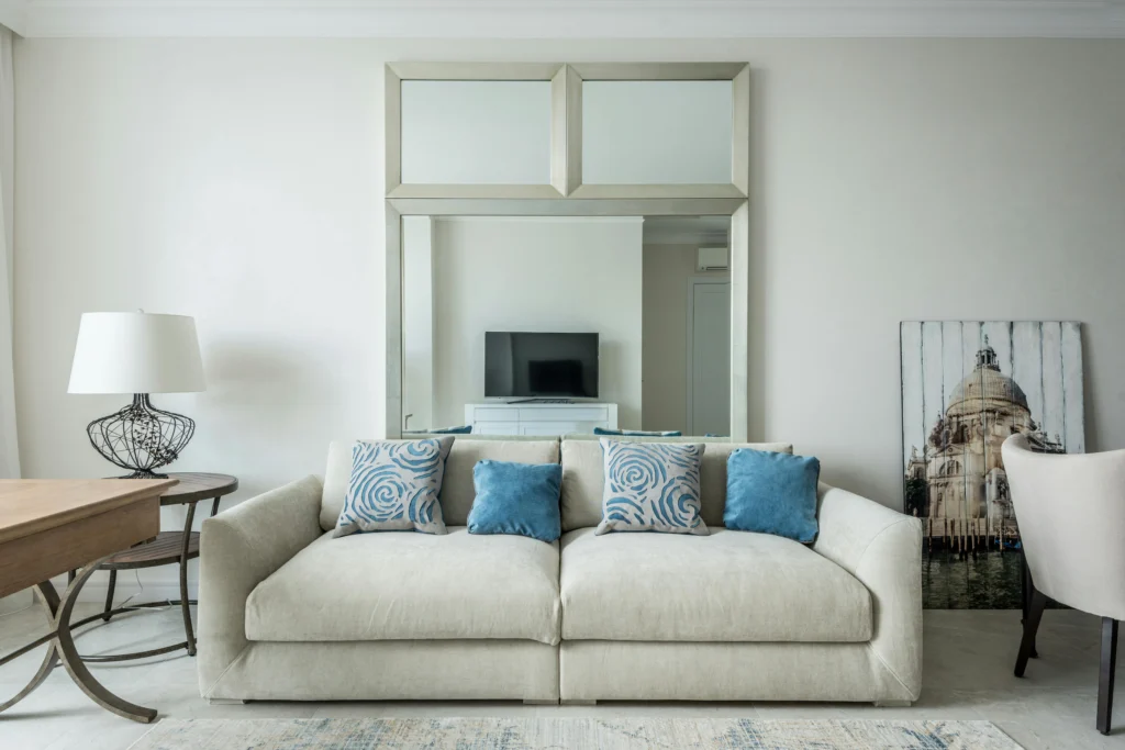 Light sofa with blue patterned pillows and large mirror