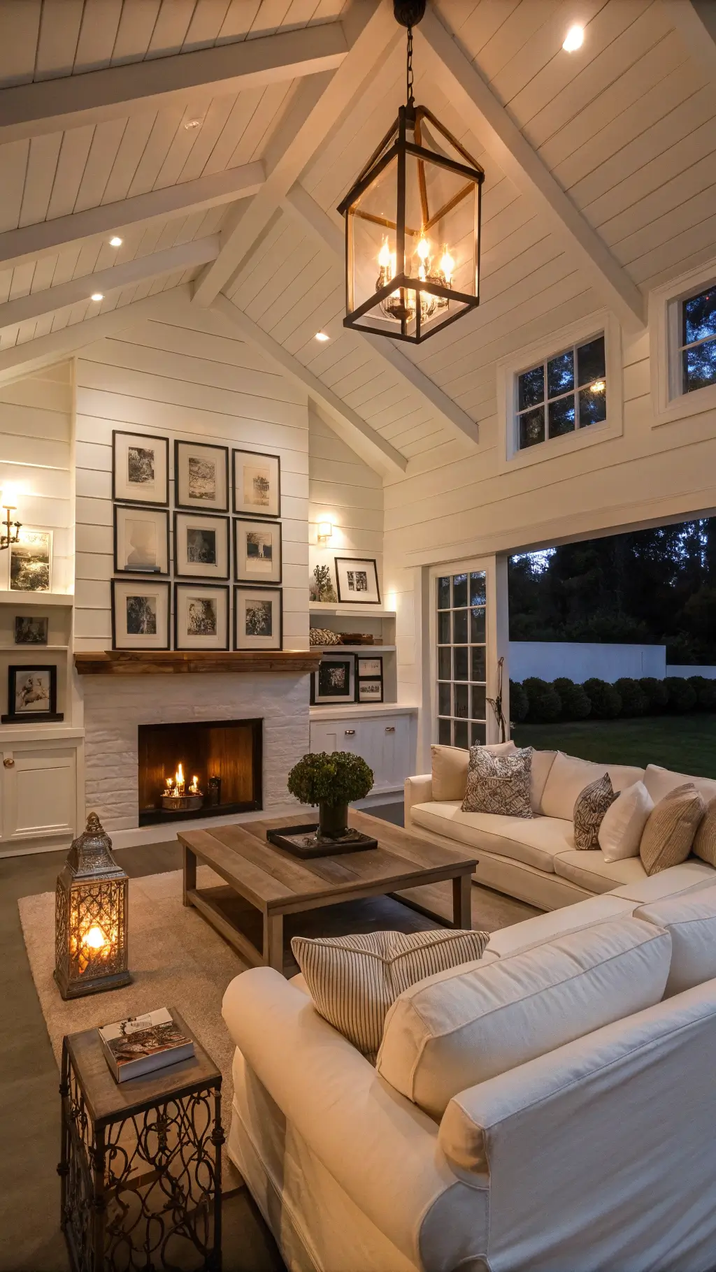 Cozy farmhouse family room with ivory sofas, distressed wood coffee table, copper lantern pendants, gallery wall of black and white photos in vintage frames, and shiplap accent wall.
