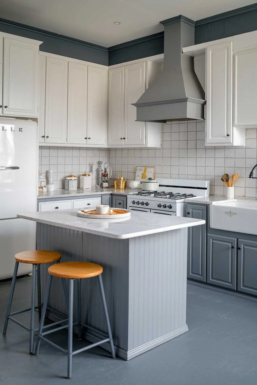 Modern kitchen featuring a gray island with a white marble countertop, white cabinetry, and gray flooring.